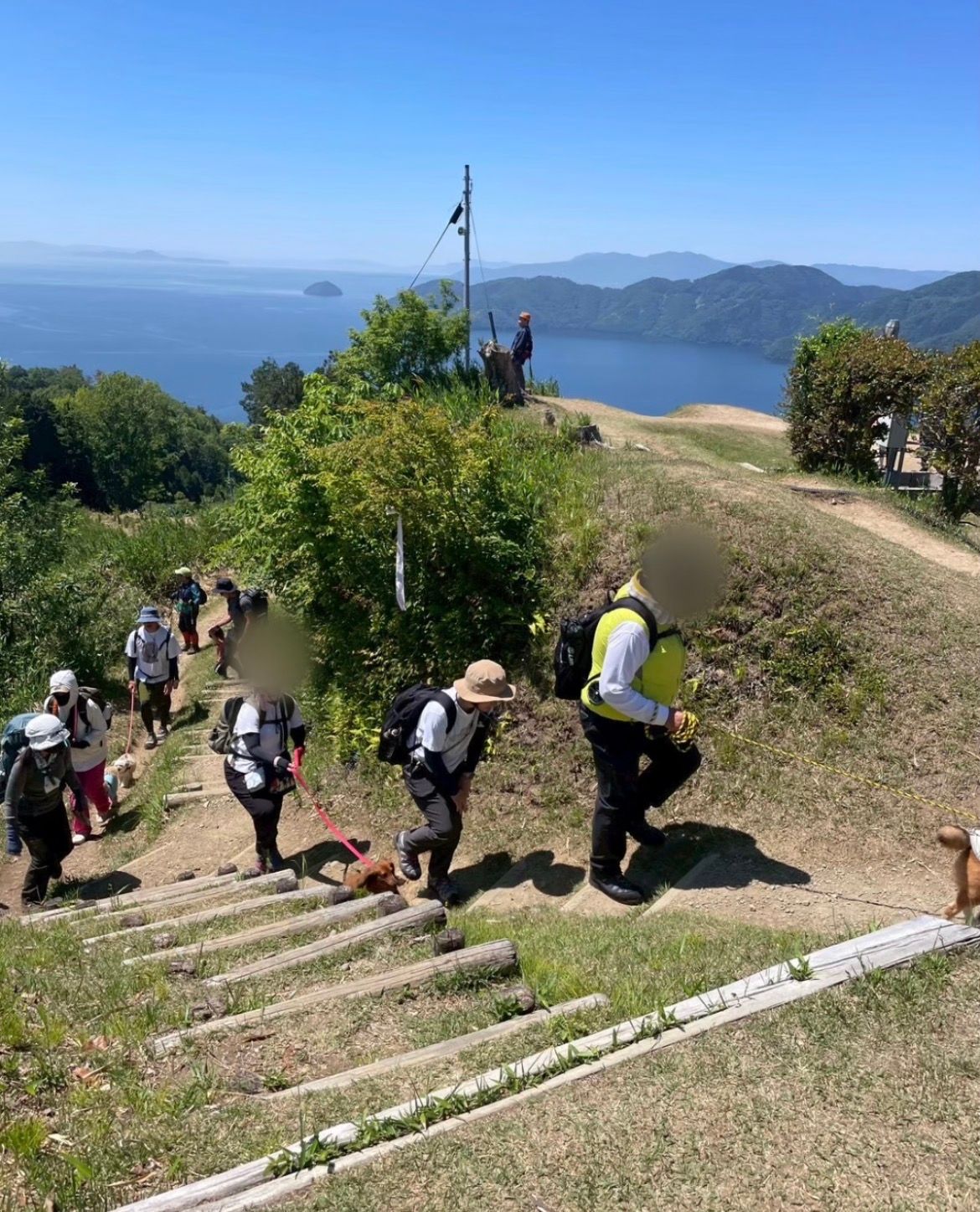 湖を望む登山道をわんこと歩く参加者たち